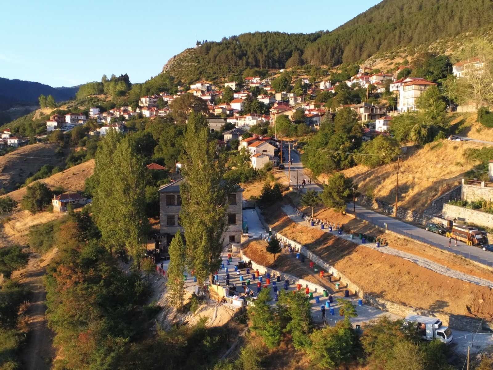 Aerial view of Kokkinopilos on the mountainside at sunset, with chairs set out for an open-air concert.